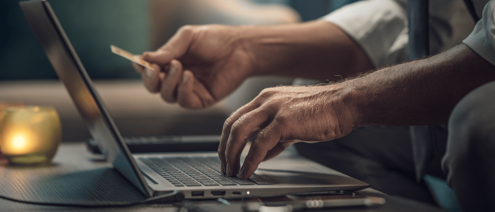 Businessman using a credit card online, he is doing online shopping and using banking services on his laptop, hands close up